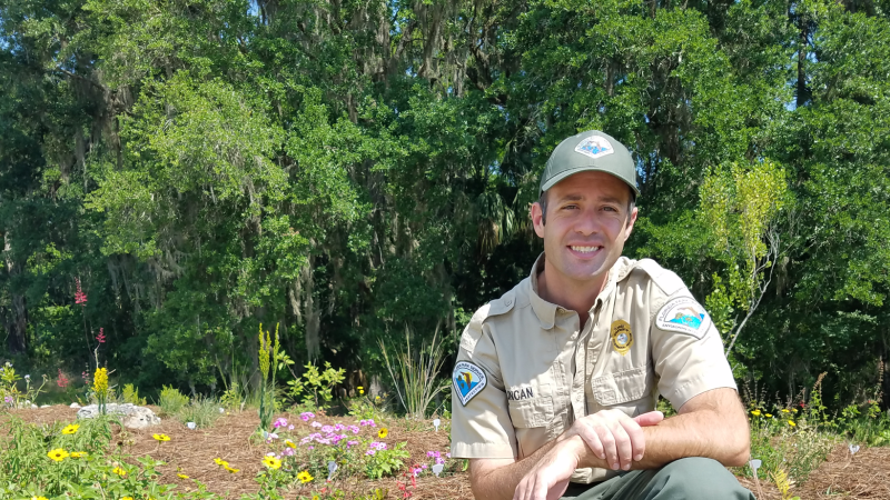 Park Manager of Colt Creek State Park smiling at the camera with a garden behind him