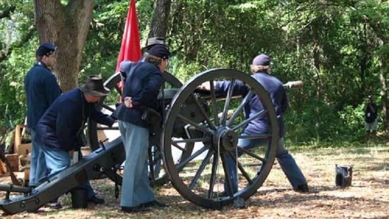 three reenactors dressed as union soldiers load a cannon