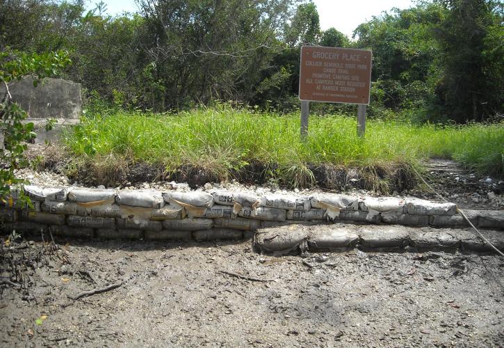 river bank with cement bags grass and brown sign