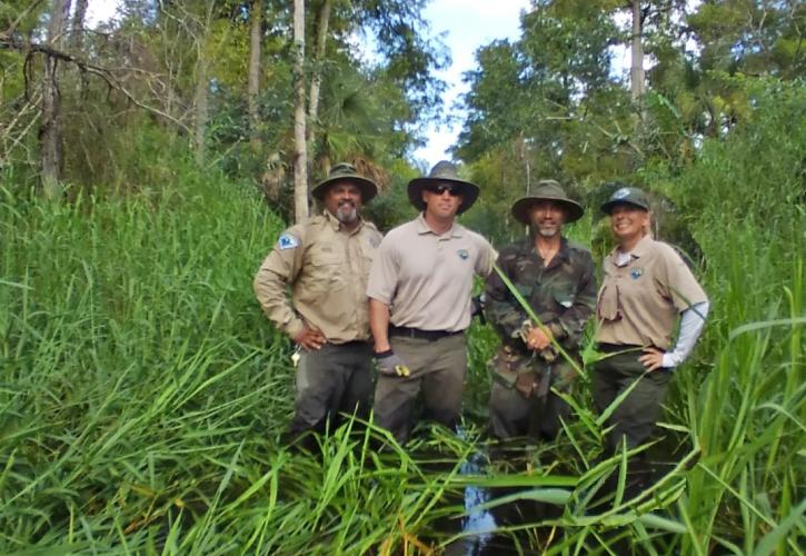 Men and a woman standing in swampy grass