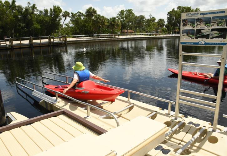 Woman pushing red kayak off canoe launch ramp