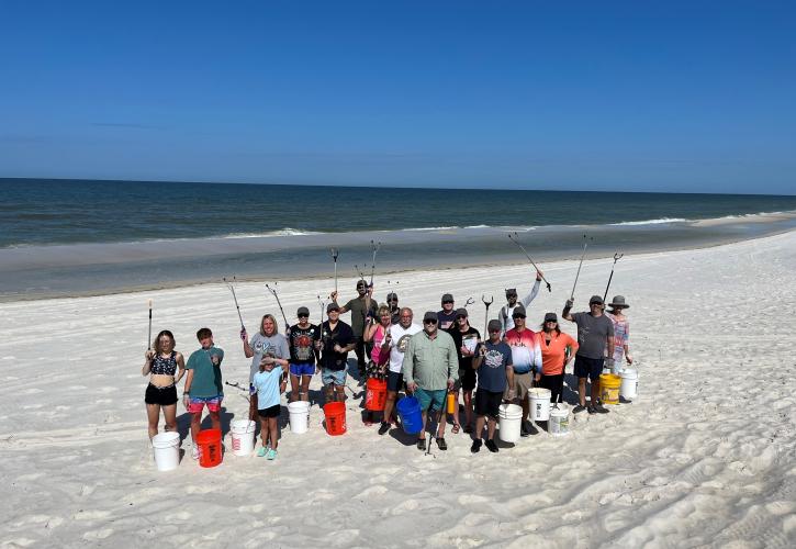 A group of people on the beach volunteering to pick up litter.