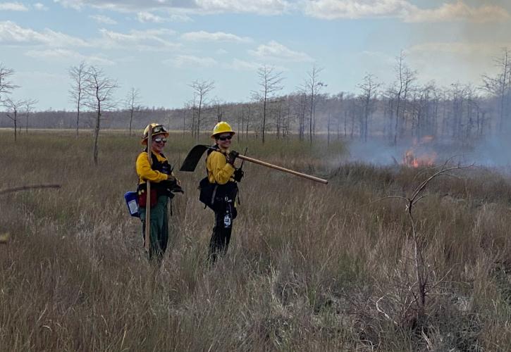 Staff members manage a fire on the prairie.