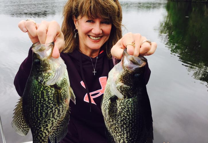 Woman holds two large fish.