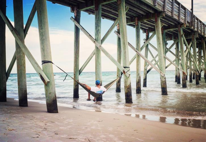 Man looks out at the water from hammock under the Gulf Pier.