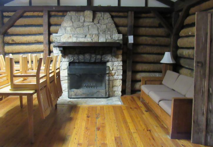 The interior of a cabin shows the table, fireplace, and couch