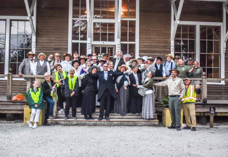 A group of volunteers stand in front of one of the historic buildings.