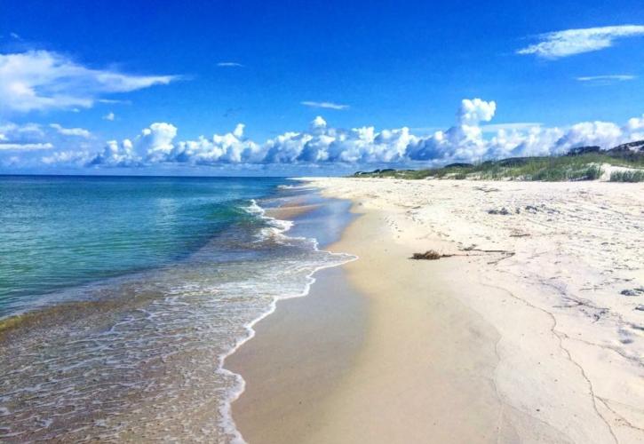 White sandy beach meets blue sky and emerald green water. 