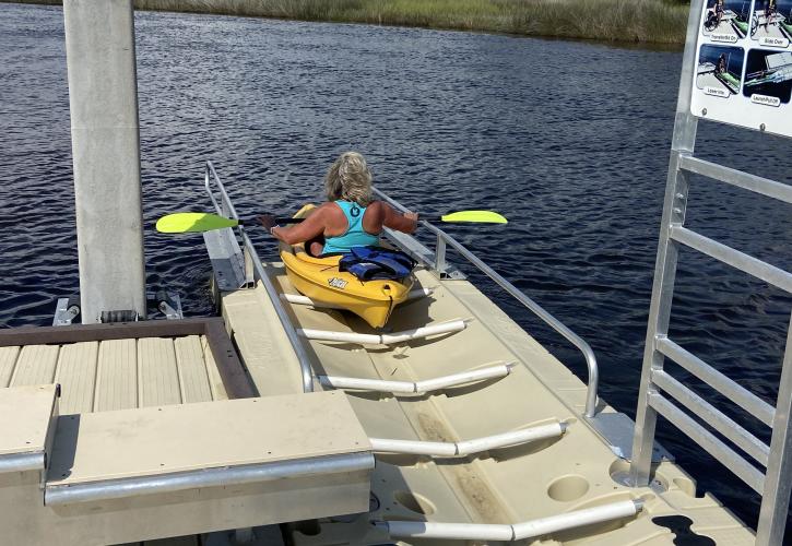 A person launches a kayak, using the accessible kayak launch amenities.