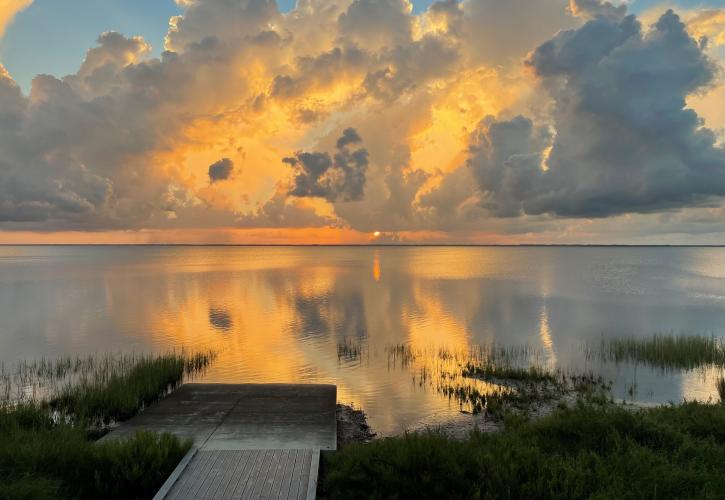 The sun rises over the bay behind the kayak/canoe launch.