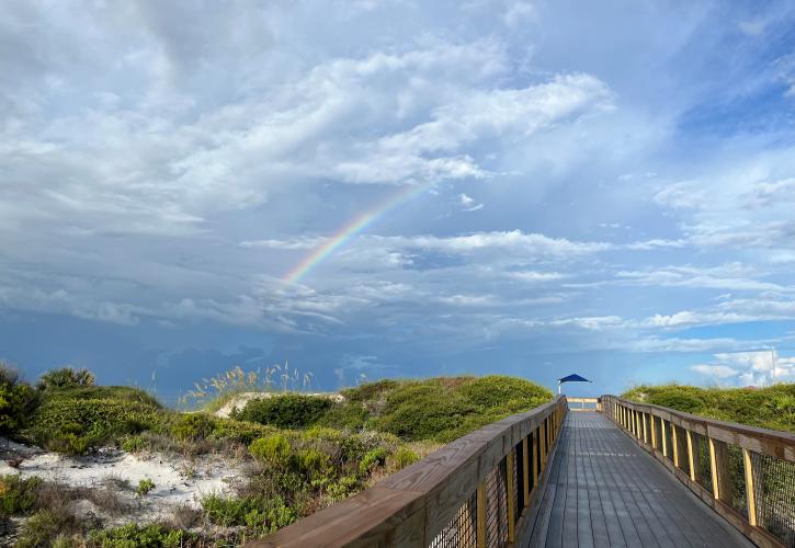 A rainbow over the boardwalk to the beach.