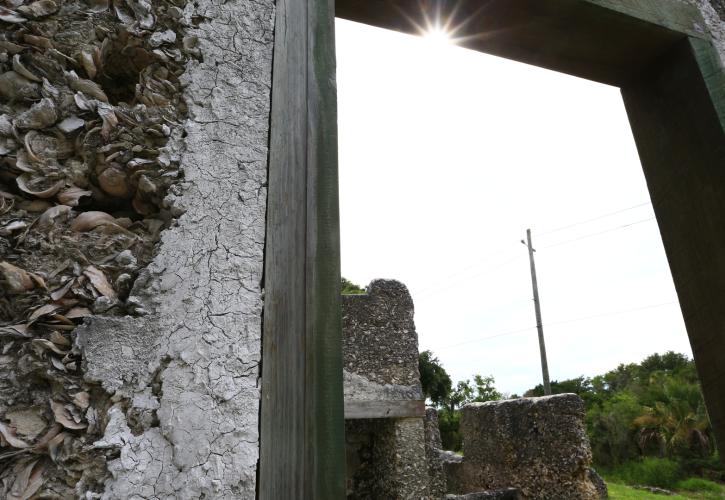 sunlight shines through a doorway within a historic shell concrete wall