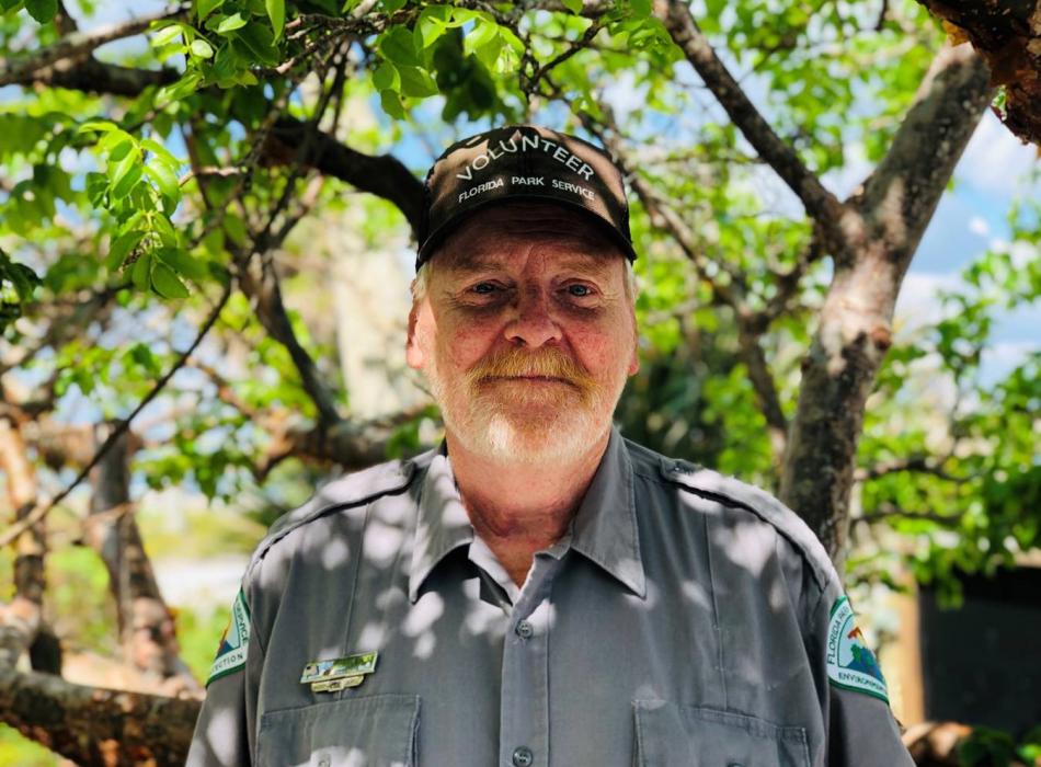 Volunteer Bob Fredericks smiling for the camera with green vegetation behind him