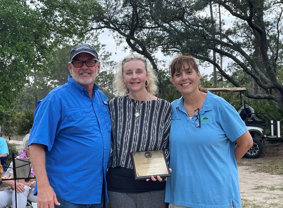 Caroline Davis receives the award from Scott Robinson and Kim Hardin at St. Andrews State Park.