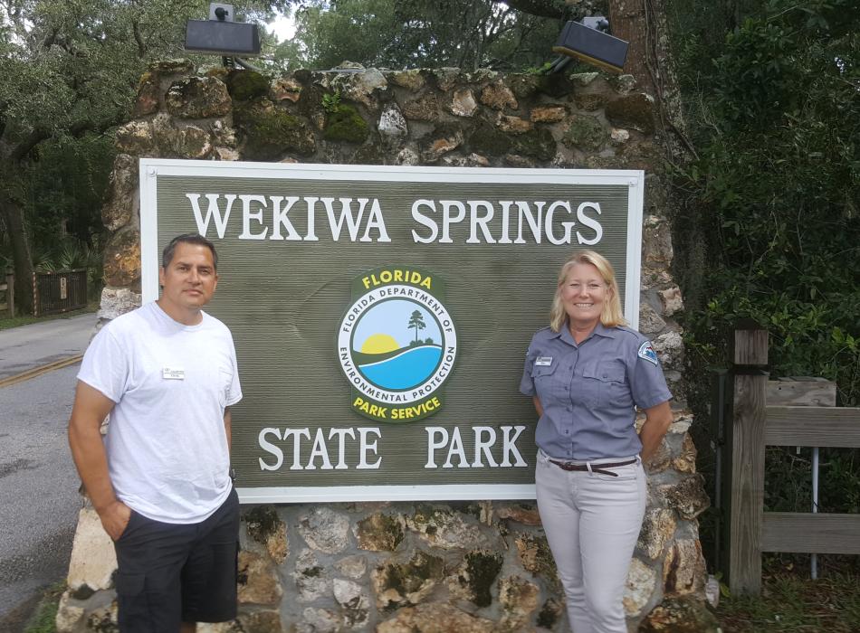 Volunteers Chris & Kim Aviles smiling with the Wekiwa Springs sign