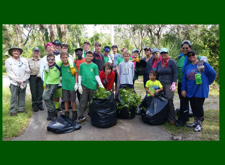 Group of adults and children with bags filled with exotic invasive plants.