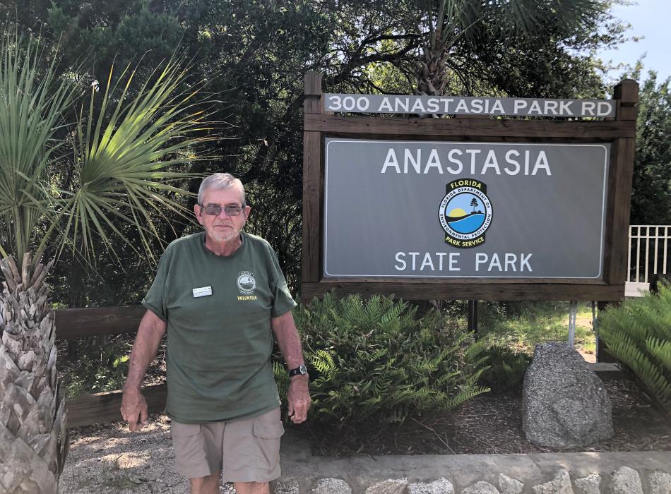 Anastasia State Park volunteer Darwin Matthews smiling for the camera with the Anastasia SP behind him