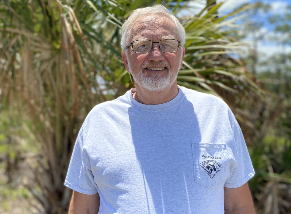 Dave Bleau volunteer stands in front of native vegetation 