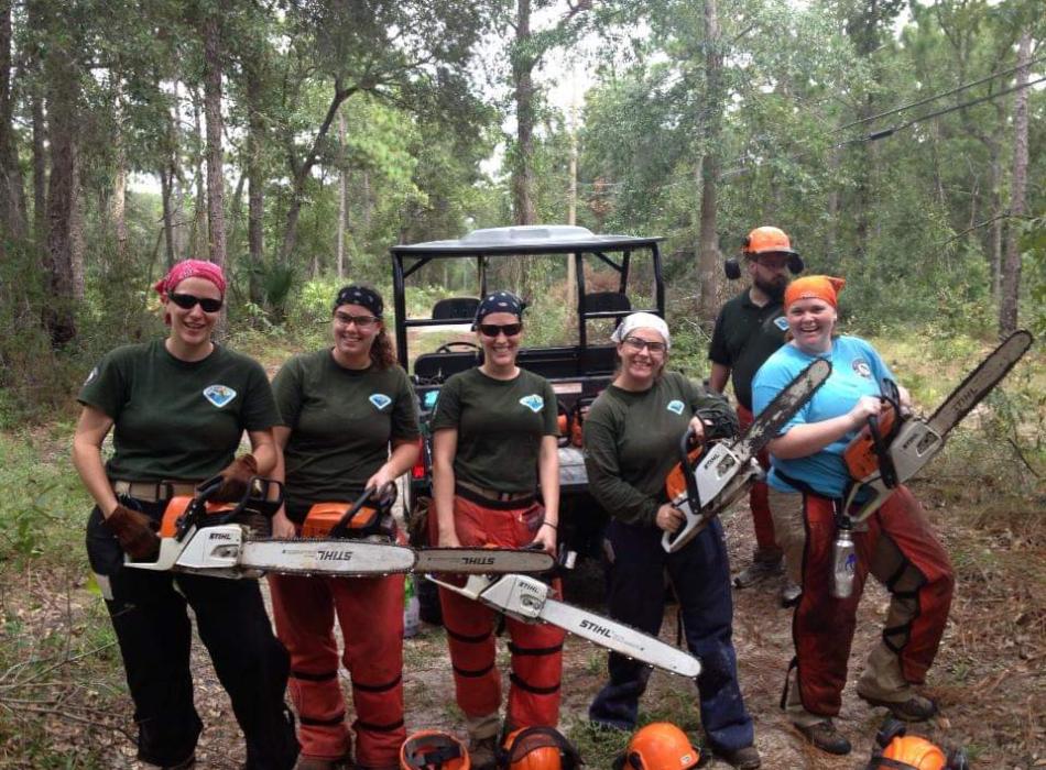 Heather Goston (wearing blue) poses with a team using chainsaws to remove non-native trees at Pumpkin Hill Creek Preserve State Park near Jacksonville.