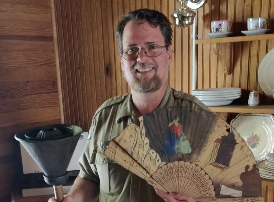 Kevin McGregor smiling at the camera holding various museum artifacts.