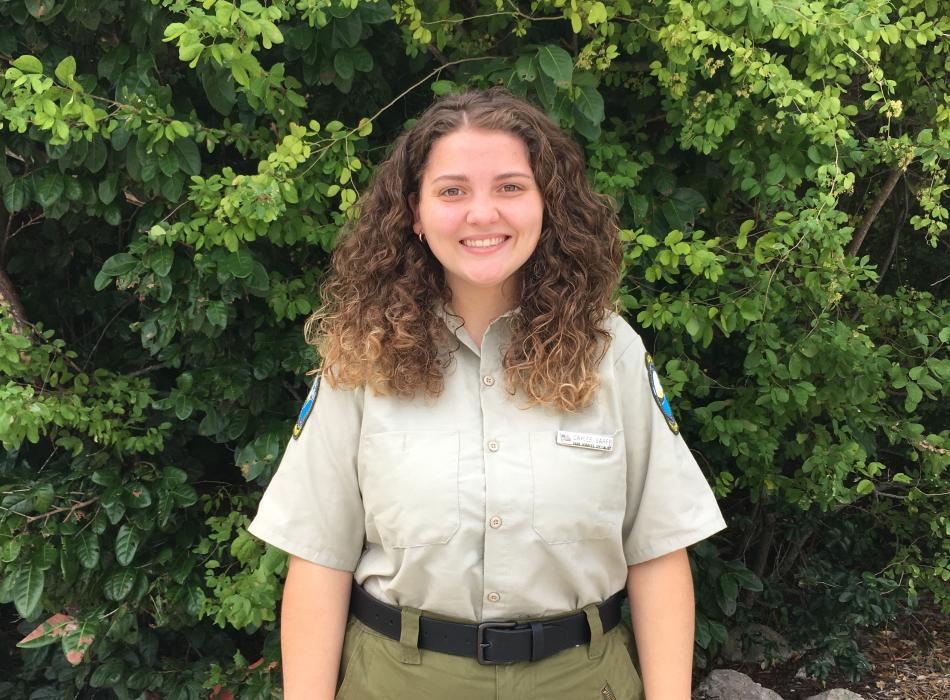 park services specialist Caylee Sarff standing in front of green vegetation.