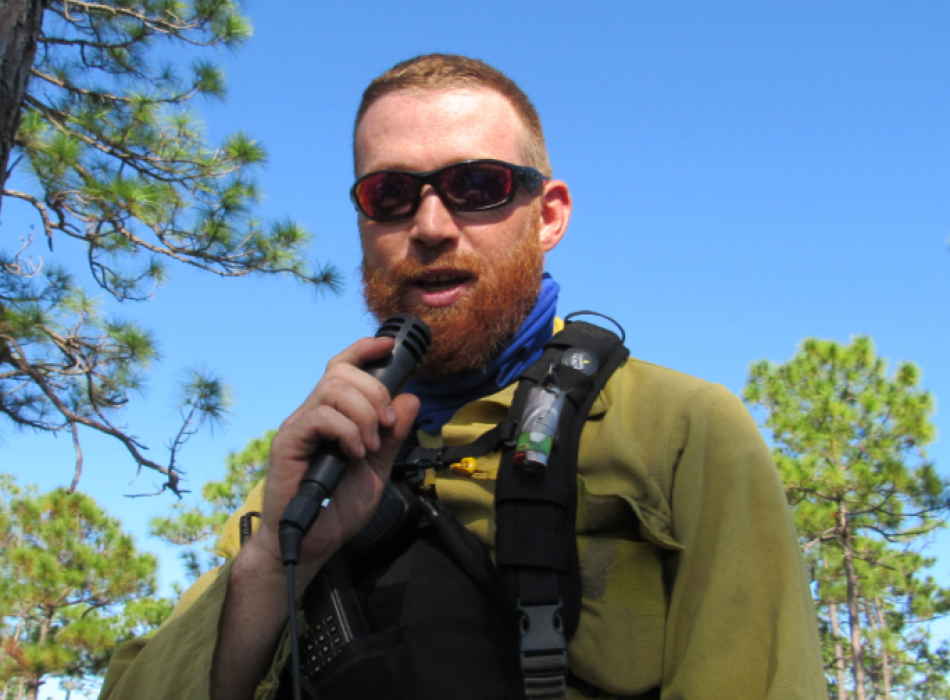 Rob, holding a microphone, possibly speaking to a group.