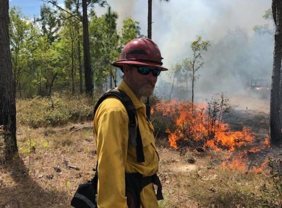 Kevin holds a drip torch during a prescribed fire.