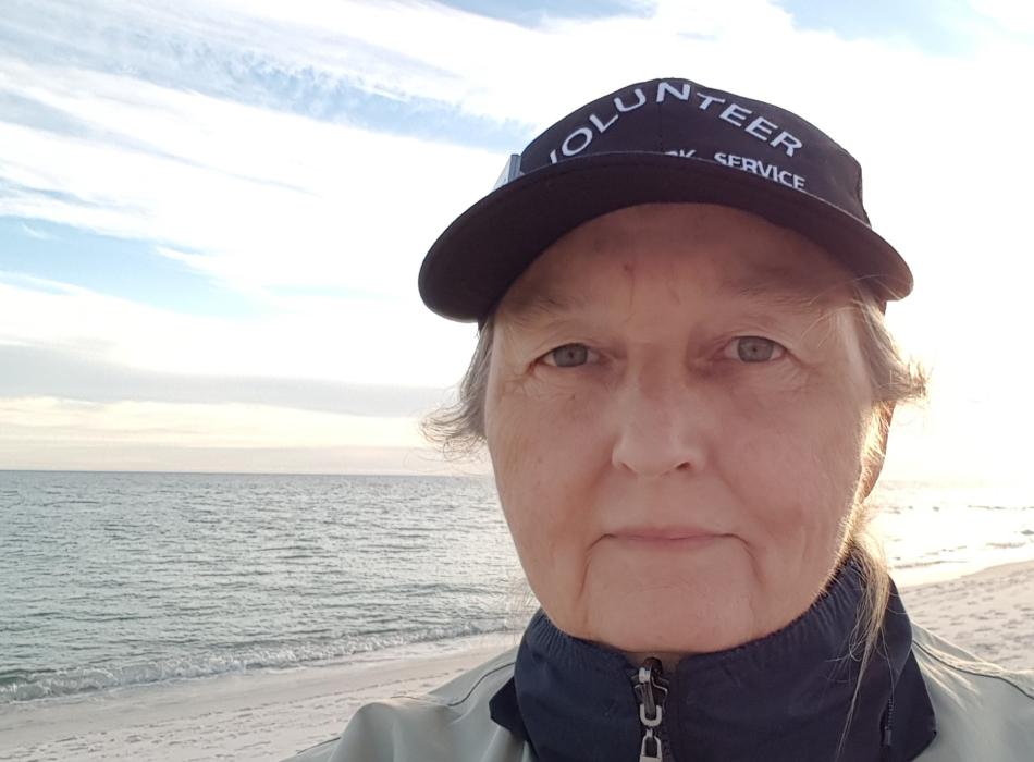 Volunteer Laura Junior proudly wears volunteer hat while walking the beach at Perdido Key. 