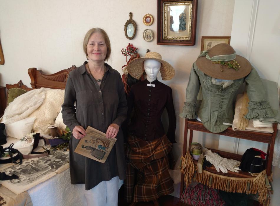 Volunteer Linda White organizes display of women's fashion that she donated to the park. 