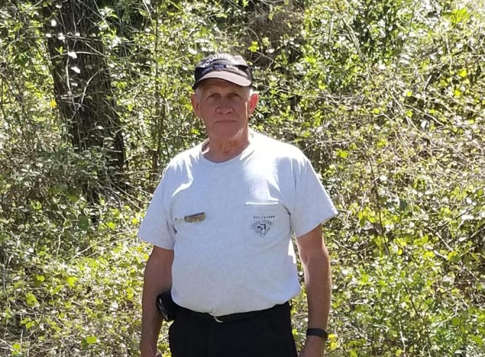 a man in a volunteer uniform stands in front of trees