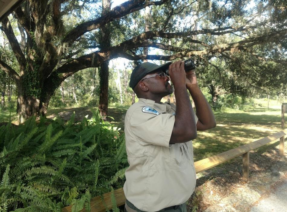 Blake Lewis using a pair of binoculars to look off into the distance.