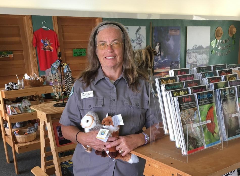 Sue Hamburger standing in the gift shop holding several stuffed animals. 