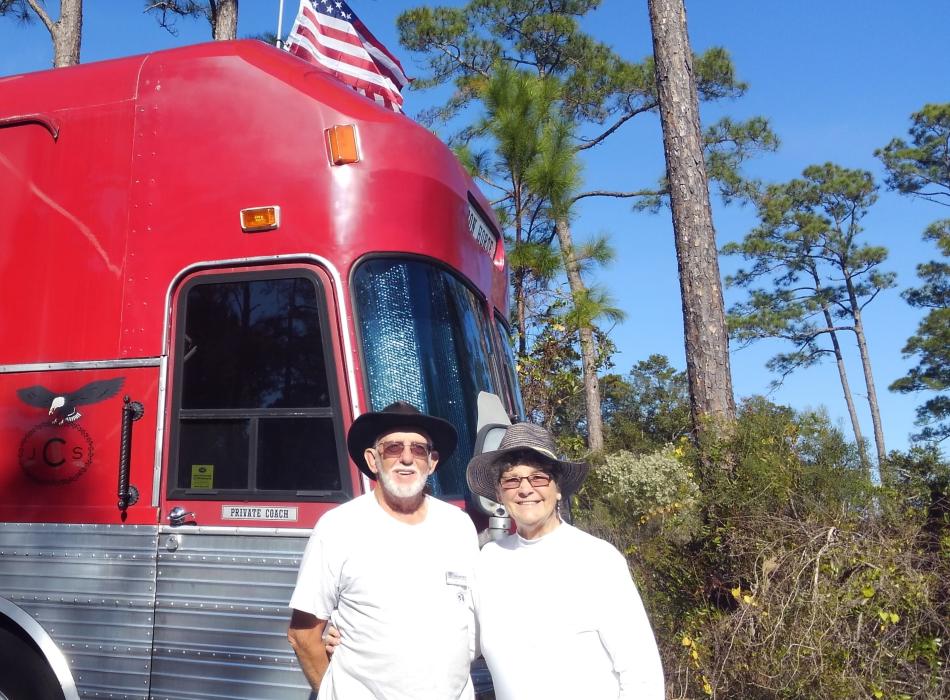 Volunteers Jimmy and Sadie Clay standing in front of their red bus known as the "Iron Horse".
