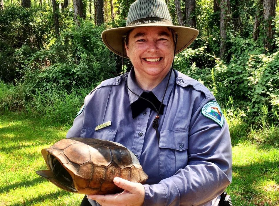 Faith, holding a gopher tortoise, smiling at the camera.