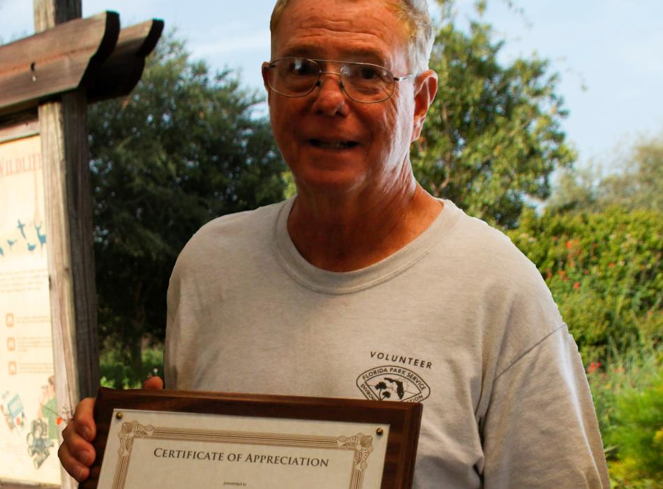 Volunteer Daniel Cleary smiling at the camera and holding an award