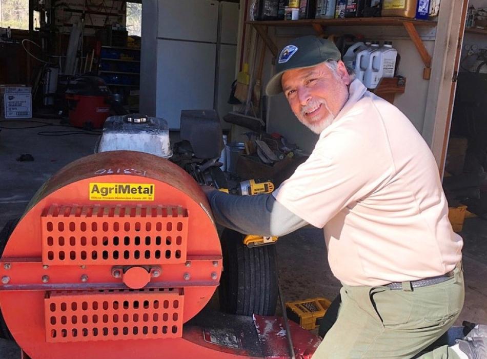 a man in park service uniform works on a red machine.